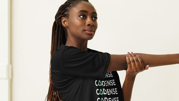 A woman stretching her arm in a black Cadense Performance T-Shirt