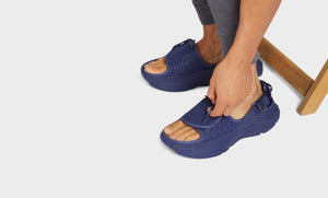 Man reaching down to touch a strap on his sandal