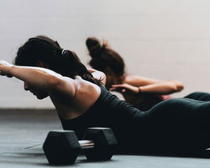 Two young women doing back strength exercises together