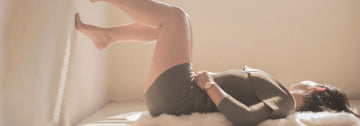 woman stretching with her legs against the wall