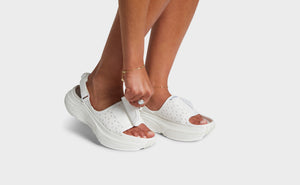 Woman reaching down to grab the strap on her sandals