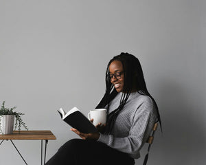 Young black woman reading a book with a cup of tea
