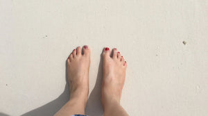 Feet with red toe nails on sandy beach