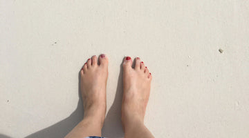 Feet with red toe nails on sandy beach