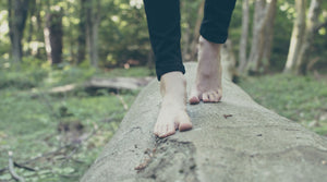 Woman walking barefoot on a log in the forest