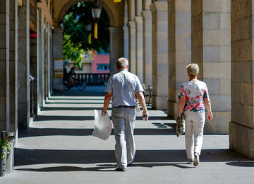 Elderly couple walking on the beach with a walker