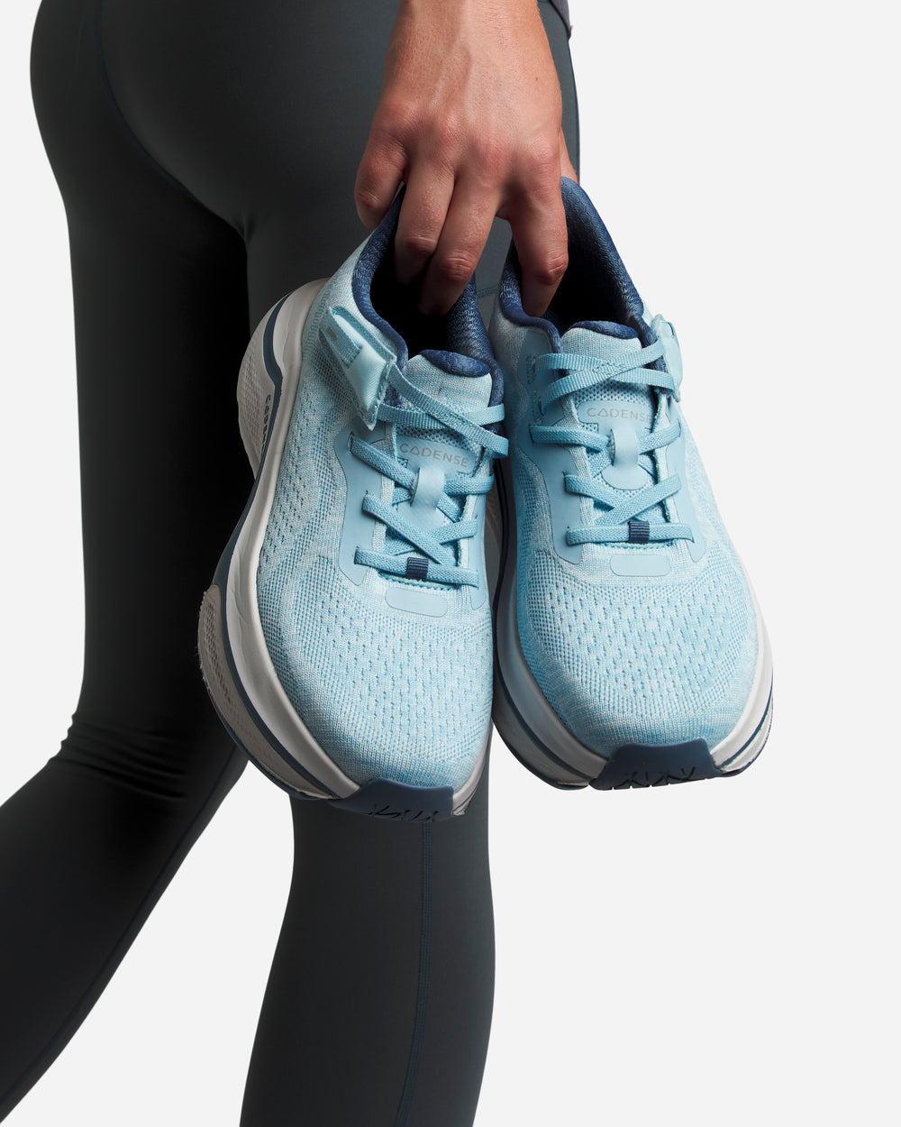 A woman holding a pair of blue Cadense sneakers