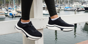 Woman sitting on pier with black adaptive sneakers by Cadense