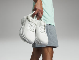 Young man holding a pair of white sneakers