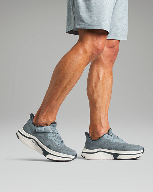 Man wearing slate colored sneakers, walking.