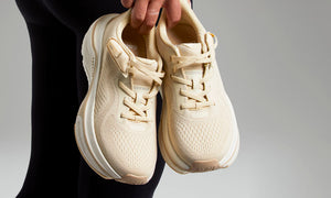 Woman holding champagne colored adaptive sneakers